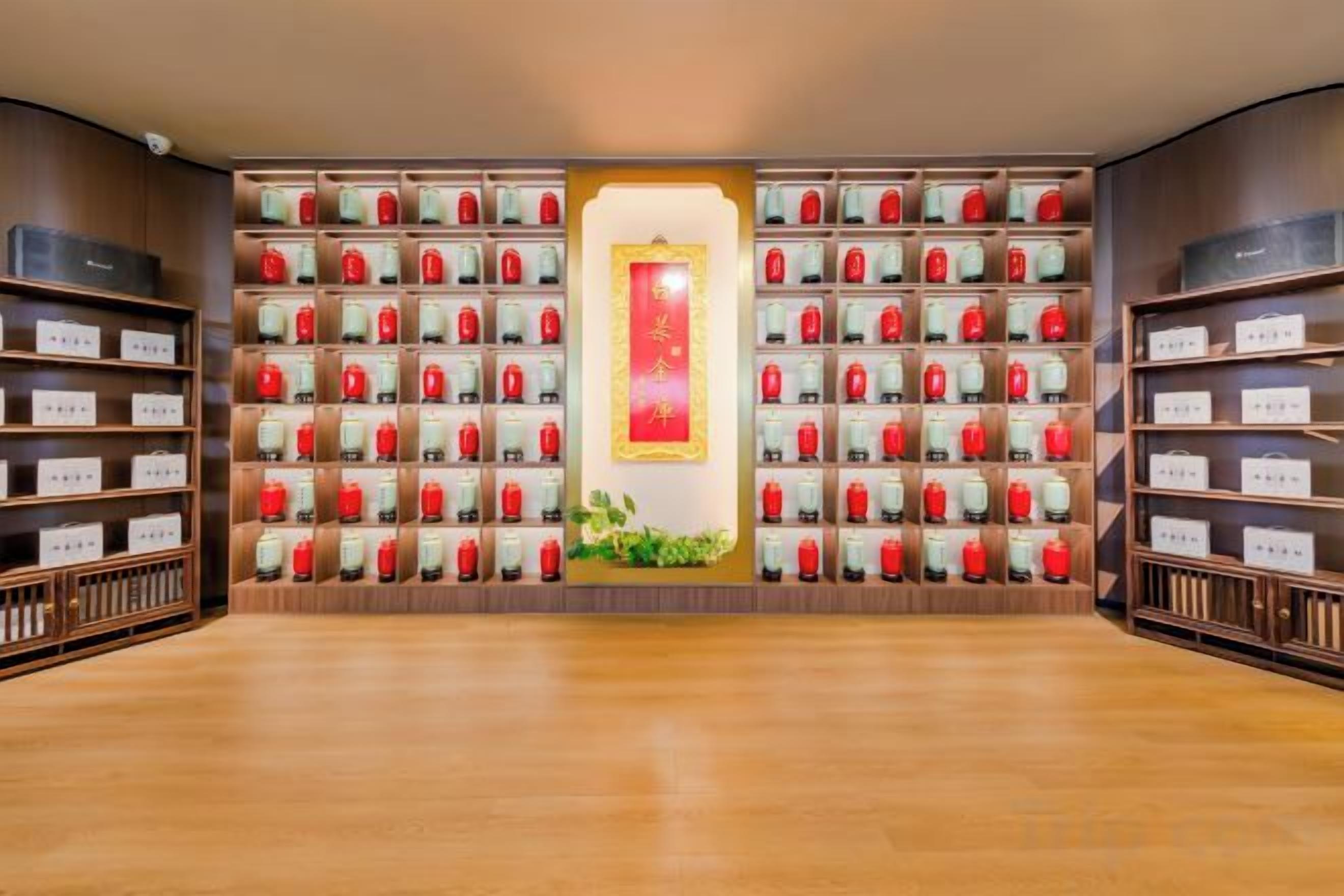A room with a wooden floor, a central aisle, and shelves on both sides filled with red and white boxes.