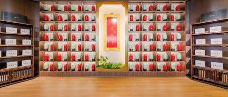 A room with a wooden floor, a central aisle, and shelves on both sides filled with red and white boxes.
