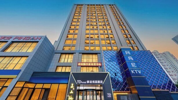 A modern hotel building with a prominent entrance, large windows, and signage for TD Hotel and KTV. - Youpin Hotel (Linyi)