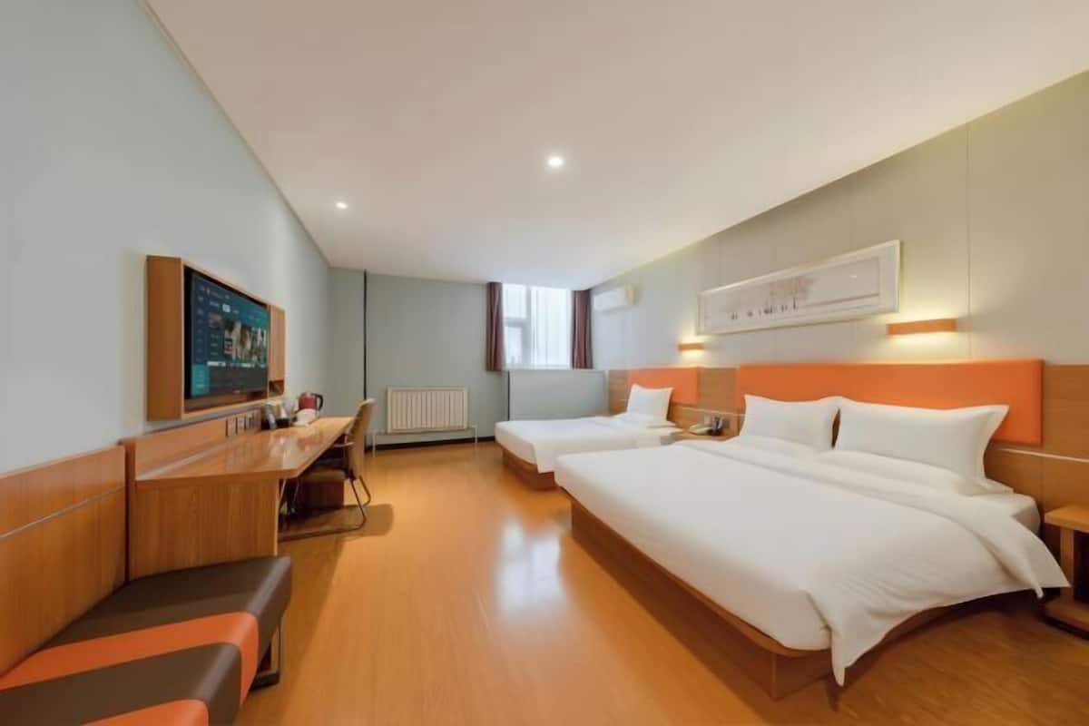 A hotel room with a bed, a desk, a chair, a TV, and a window.