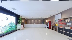 A modern hotel lobby with a reception desk, a large mural on the left, and a storage area with boxes on the right. - Youpin Hotel (Linyi)