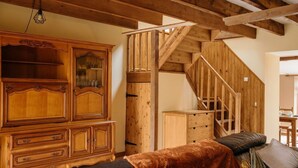 A wooden staircase with a simple design, a large wooden cabinet with multiple drawers, and a cozy sofa with a blanket. - Mézon Maëlle, ideal for families and friends (Teillay)