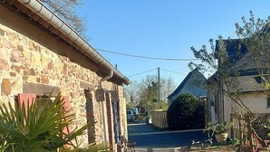 A paved street with stone buildings on either side, a bench, and a large potted plant. - Mézon Maëlle, ideal for families and friends (Teillay)