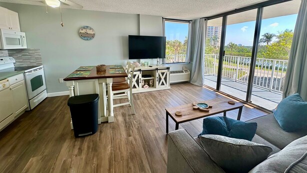 Ein modernes Wohnzimmer mit einer Couch, einem Couchtisch, einem Essbereich mit Tisch und Stühlen, einem Fernseher und einem Balkon mit Blick.