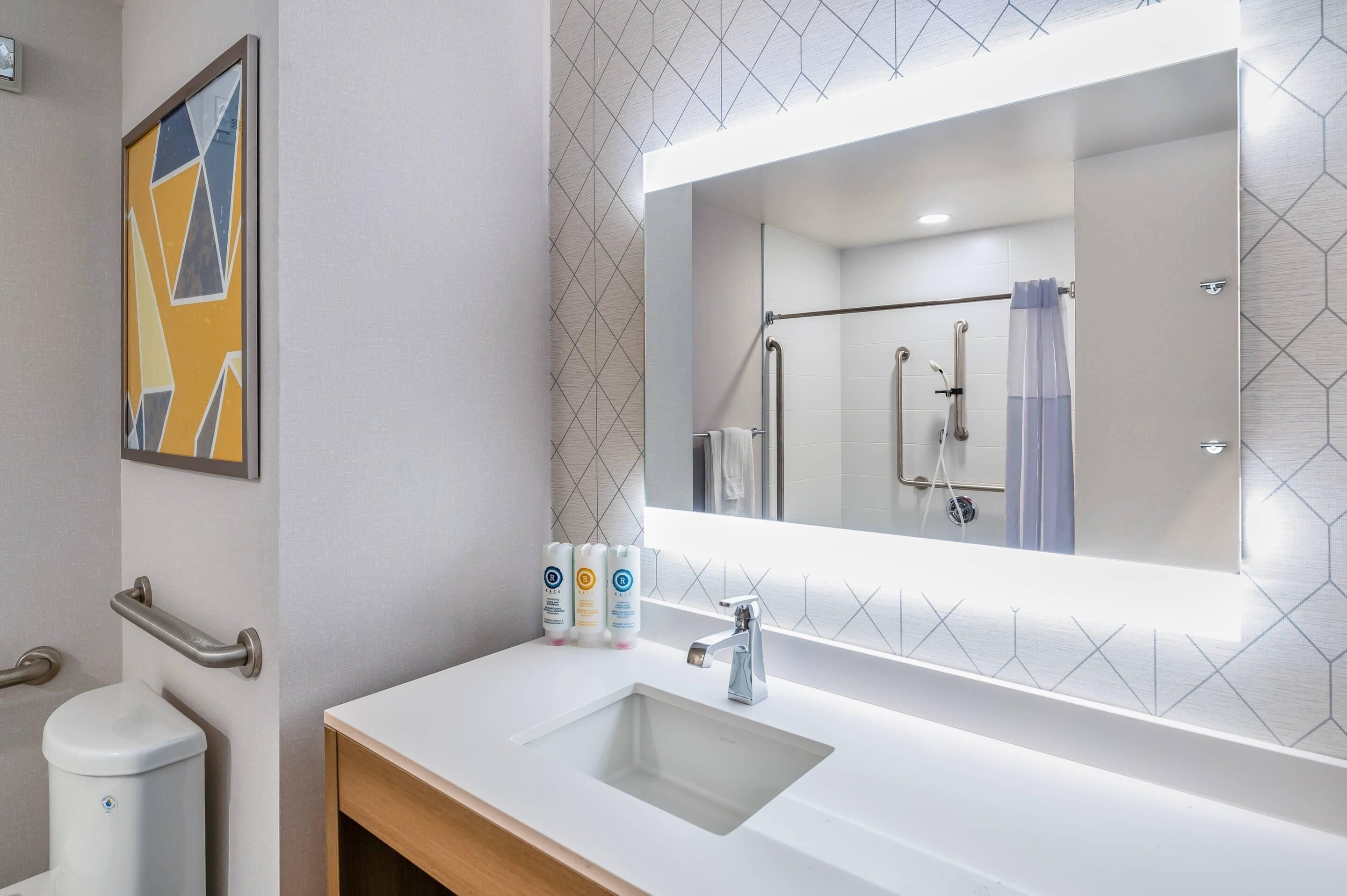 Un baño moderno con un lavamanos blanco, un espejo grande y una zona de ducha.