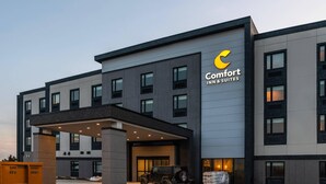 Un bâtiment moderne de l’hôtel Comfort Inn & Suites, doté d’une entrée couverte et d’un VUS stationné devant.