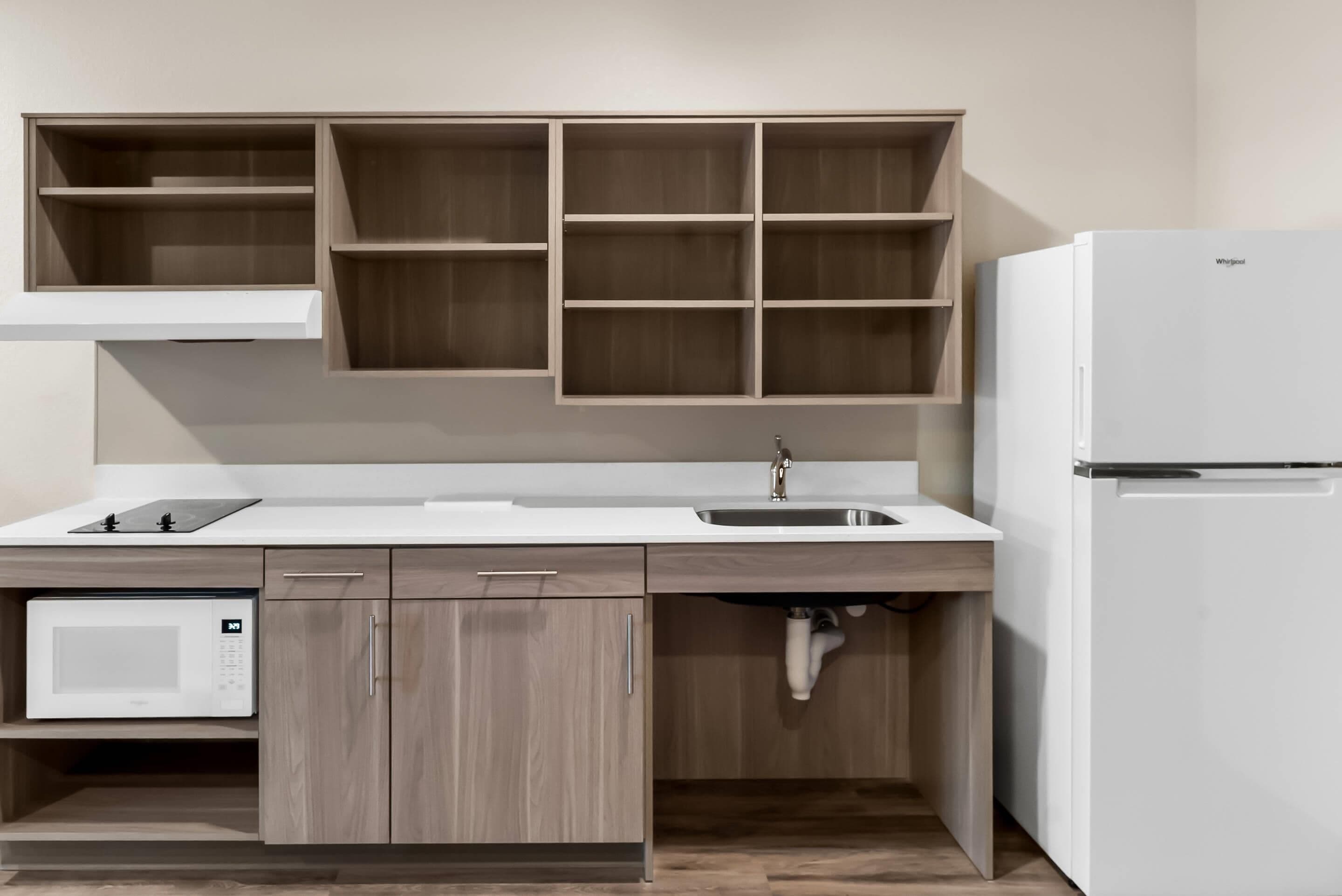 A modern kitchen with a built-in microwave, a sink, and a refrigerator.