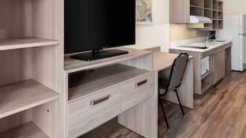 A modern kitchen with a flat-screen TV, wooden cabinetry, and a built-in sink.