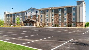 A multi-story hotel with a stone facade and a parking lot in front. - Woodspring Suites Greenville Airport (Greenville)