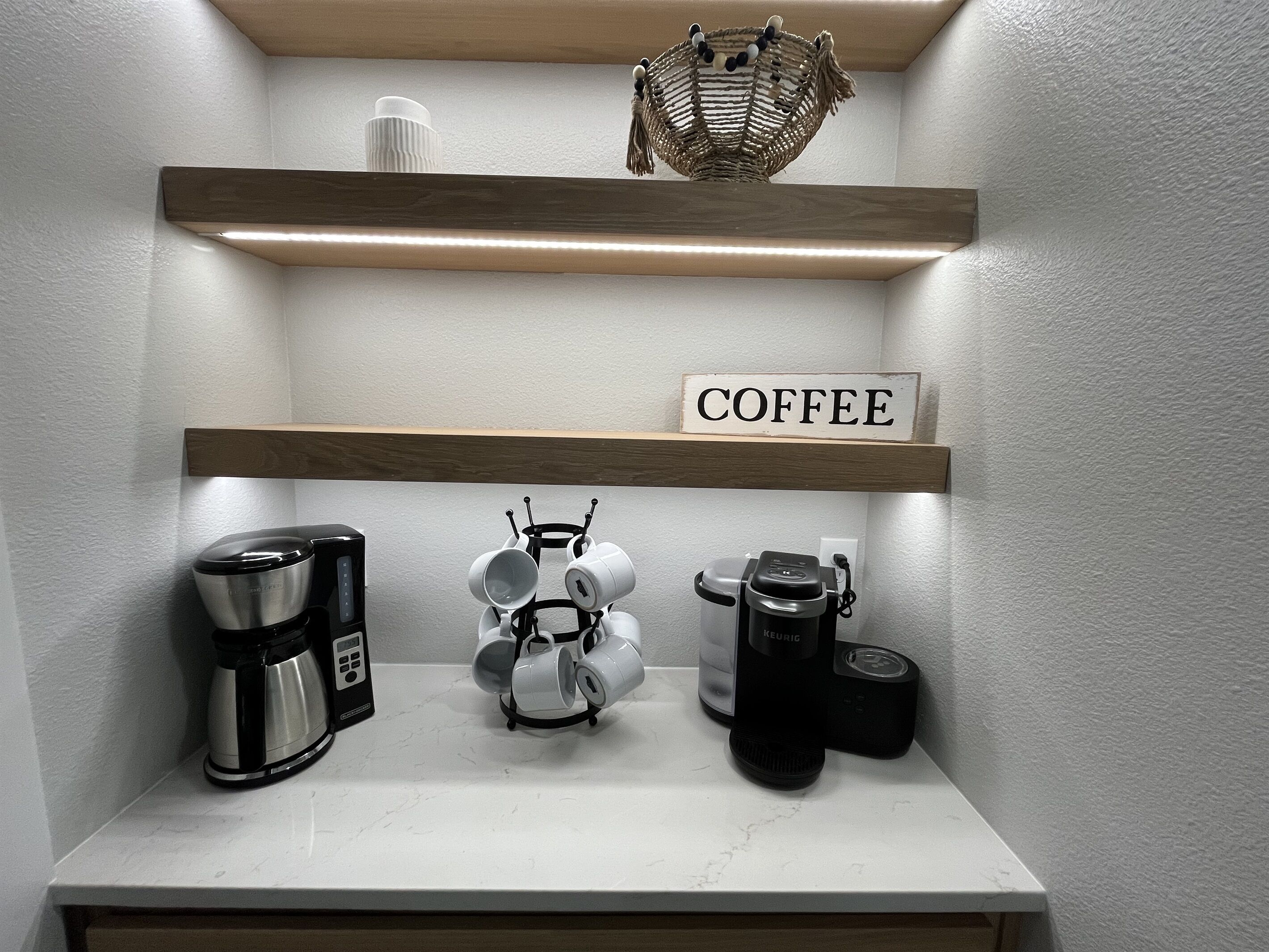 A kitchen counter with coffee-making equipment, including a coffee maker, a kettle, and a coffee grinder.