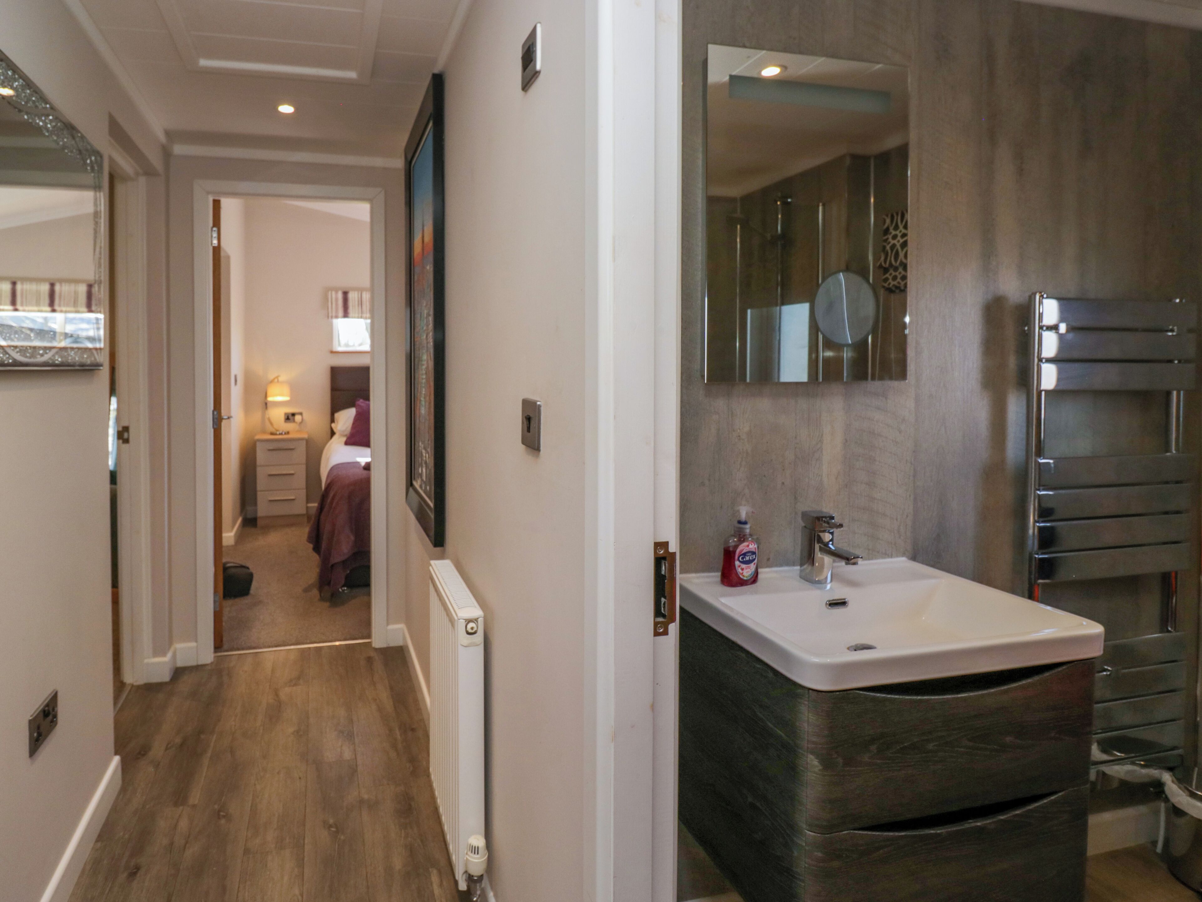 A modern bathroom with a large mirror, a sink, and a towel rack.