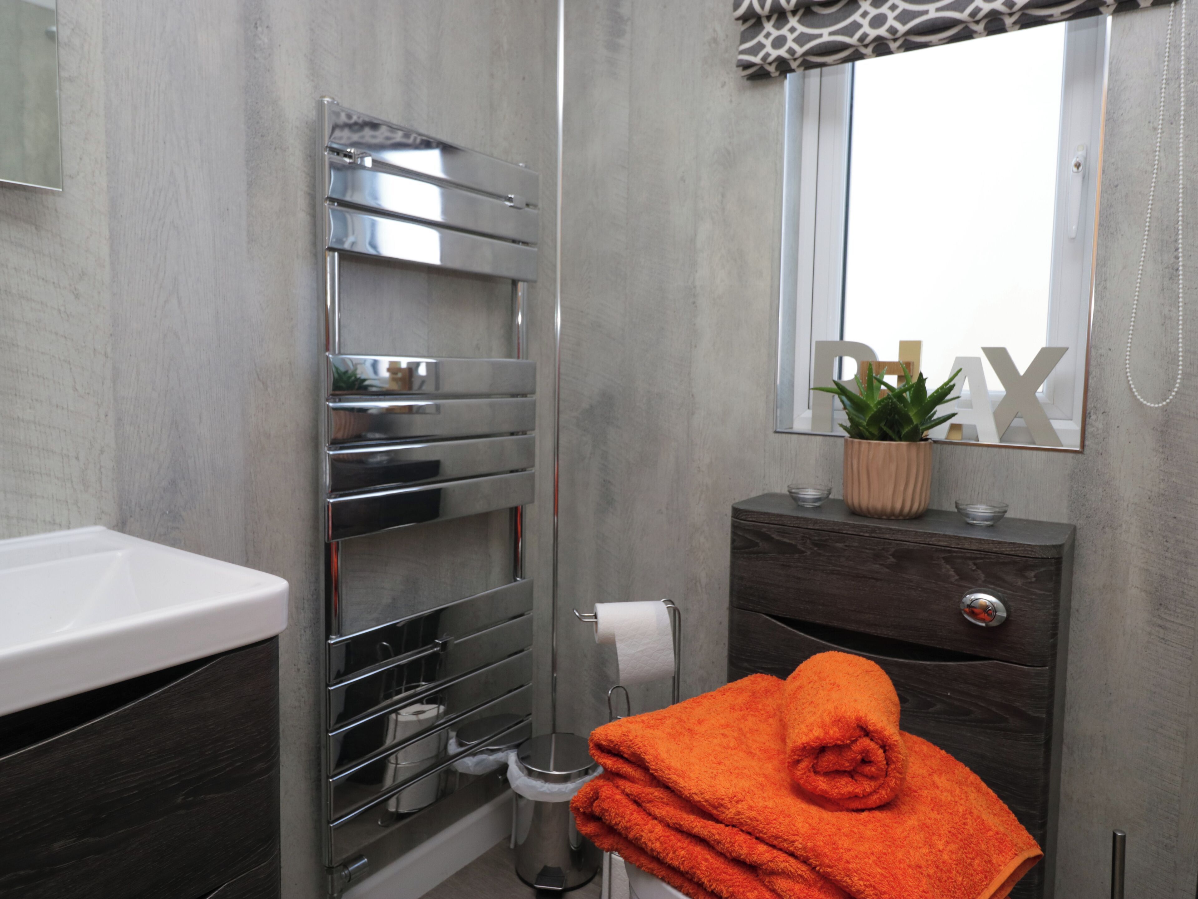 A modern bathroom with a built-in towel rack, a wooden vanity, and a mirror above the sink.