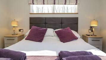 A hotel room with a large bed, two nightstands, a window with a view of trees, and a headboard.