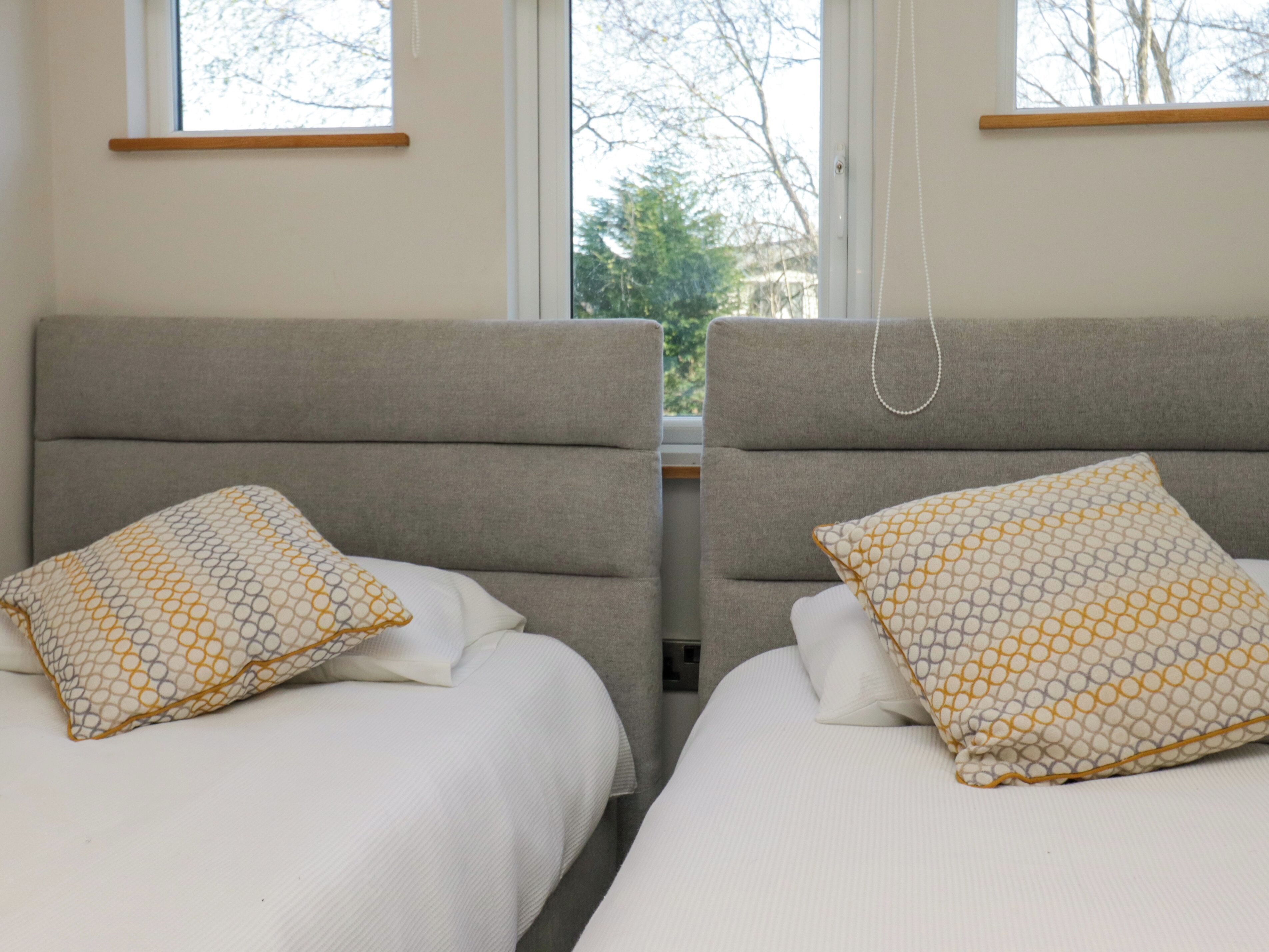 A double room with two beds, each with a patterned pillow and a headboard.