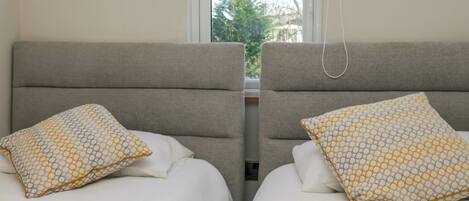 A double room with two beds, each with a patterned pillow and a headboard.
