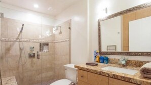 A bathroom with a glass-enclosed shower, a toilet, a sink with a marble countertop, and a large mirror with a decorative frame. - Chic 1-bedroom apartment with AC, WiFi in fabulous West Hollywood (West Hollywood)