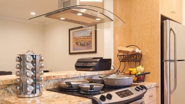 A modern kitchen with granite countertops, a gas stove, a stainless steel range hood, a built-in oven, and a refrigerator. - Chic 1-bedroom apartment with AC, WiFi in fabulous West Hollywood (West Hollywood)