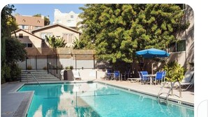 A swimming pool with a clear blue water, surrounded by lounge chairs and a blue umbrella. - Chic 1-bedroom apartment with AC, WiFi in fabulous West Hollywood (West Hollywood)