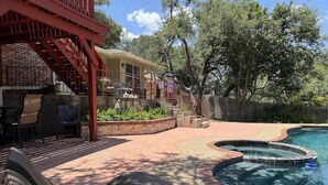 Ein Garten mit Pool, Sitzgelegenheiten im Freien und einer überdachten Terrasse.
