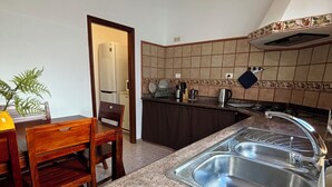 Eine Küche mit einer Granitabdeckung, einer Edelstahlspüle und einem Essbereich mit Holztisch und Stühlen.