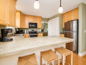 A kitchen with wooden cabinets, a stainless steel refrigerator, a built-in microwave, and a coffee maker. - Lakefront, Dock, Kayaks, Paddle Boards, Pet Friendly, Fire pit (Littleton)