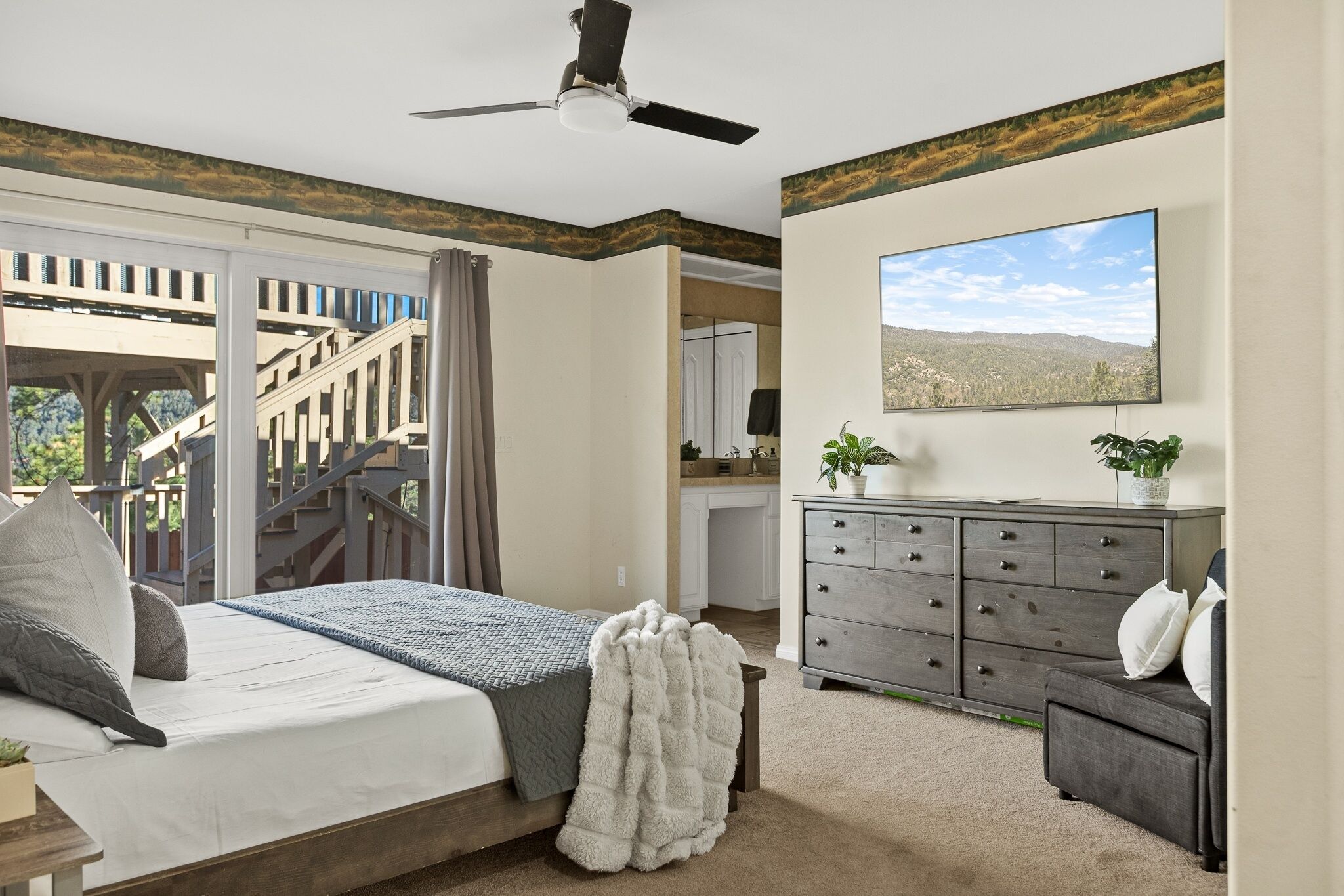 Une chambre à coucher comprenant un lit, une commode, un bureau et un téléviseur.