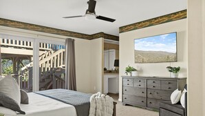 Un dormitorio con cama, cómoda, escritorio y televisor.