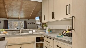 Una cocina moderna con armarios de madera, un salpicadero de piedra y una estación de café integrada.