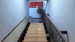 A staircase with alternating beige and black steps, a metal railing, and a potted plant on the right. - Shuanggang Hotel (Shanghai)