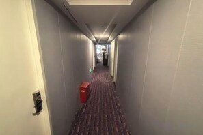 A hotel hallway with a carpeted floor, a red box, and a door on the left. - Shuanggang Hotel (Shanghai)