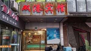 A hotel entrance with a large sign in red characters, a glass door, and a welcome sign. - Shuanggang Hotel (Shanghai)