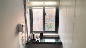 A small kitchenette with a window, a telephone, and a kettle on the counter.