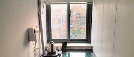 A small kitchenette with a window, a telephone, and a kettle on the counter.