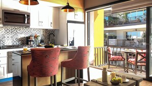 Une cuisine moderne équipée d’un four à micro-ondes, d’une machine à café et d’un coin repas avec des chaises rouges et une table.