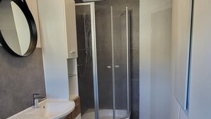 A modern bathroom with a white vanity, a glass shower enclosure, and a small rug on the floor. - Vacation apartment / fitter's apartment / short-term rental (Schönborn)