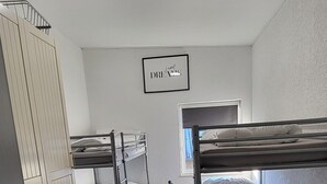 A dormitory room with bunk beds, a small table, and a framed inspirational quote on the wall. - Vacation apartment / fitter's apartment / short-term rental (Schönborn)