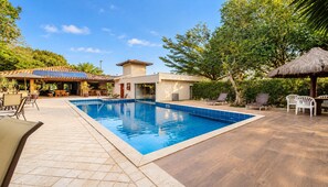 A swimming pool with tiled edges, surrounded by lounge chairs and a covered seating area. - Bz21 Casa com Jacuzzi e churrasqueira (Buzios)