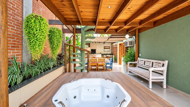 A spa area with a hot tub, wooden flooring, a bench, and a staircase leading to an upper level. - Bz21 Casa com Jacuzzi e churrasqueira (Buzios)