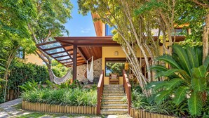 A tropical garden with a hammock, a stone staircase, and a wooden pergola. - Bz21 Casa com Jacuzzi e churrasqueira (Buzios)