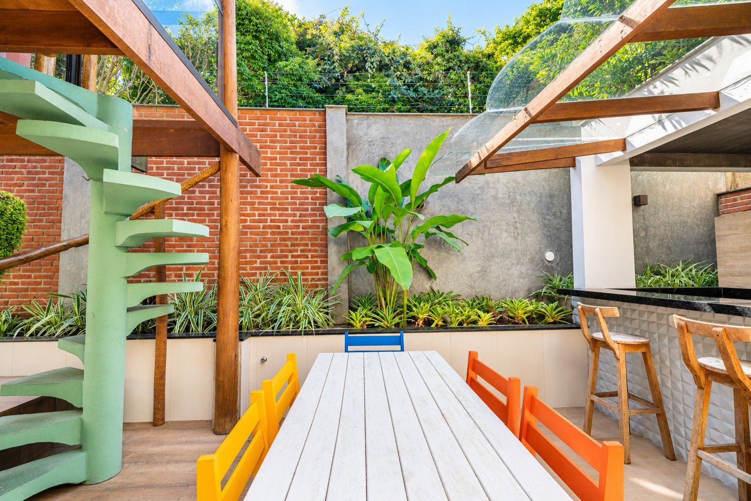 A patio with a wooden table and chairs, surrounded by plants and a brick wall.