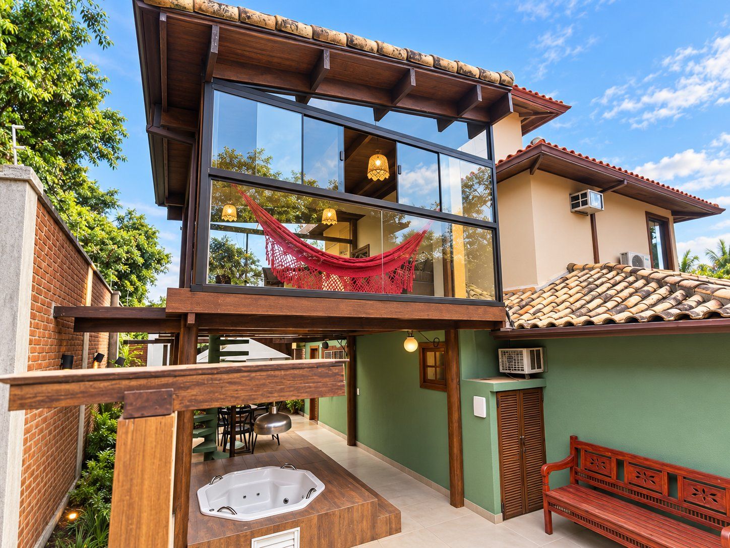 Un edificio moderno con balcón de vidrio, jacuzzi y hamaca.
