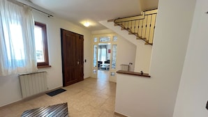 A hallway with a wooden bench, a radiator, a door, and a staircase.