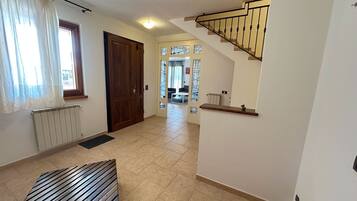 A hallway with a wooden bench, a radiator, a door, and a staircase.