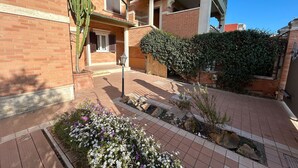 A courtyard with a brick building, a cactus, and a variety of plants.