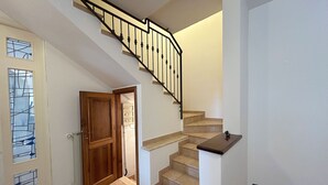 A staircase with a wooden handrail and beige steps leading to an upper floor.