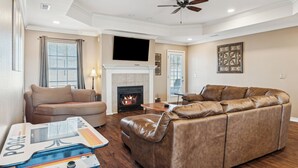 A living room with a fireplace, leather sofa, and a flat-screen TV. - Spin and Stay on Navajo (Bentonville)