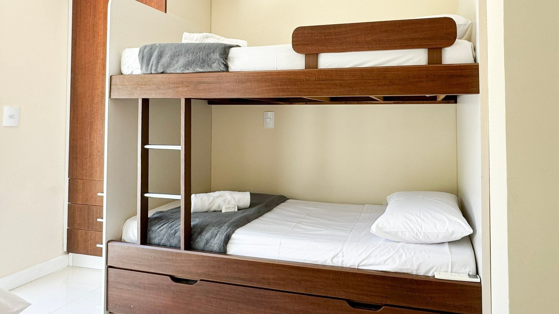 A bunk bed with a wooden frame, a lower drawer, and a ladder.