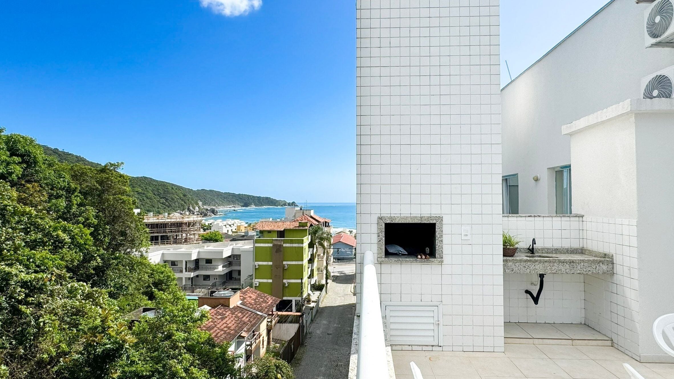 Un edificio moderno con fachada blanca, una ventana pequeña con vista al mar y suelo de baldosas.