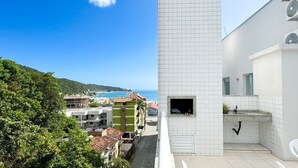 A modern building with a white facade, a small window with a view of the sea, and a tiled floor. - Cobertura com Piscina na praia de Bombas (Bombinhas)