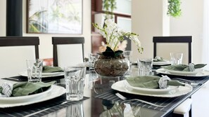 Une table à manger dressée avec des assiettes, des verres et un centre de table composé de fleurs blanches dans un vase en verre.